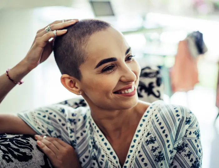 A photo of a smiling woman with post-cancer treatment hair loss.